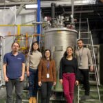 Five researchers standing in front of an AstroCeNT backdrop with the text “Explore the Hidden Universe” during a formal scientific event.